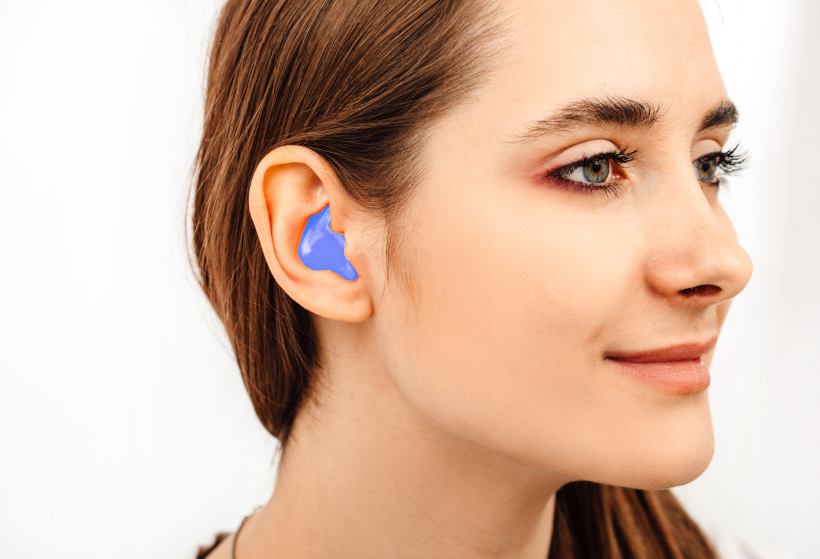 A young woman wearing impressions which will be used to create custom earplugs
